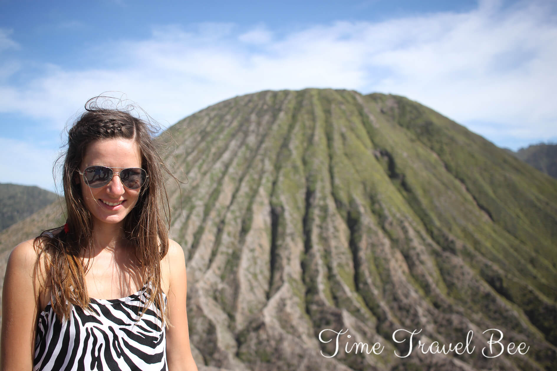 Girl visiting indonesia green hills of bromo volcano, volcanic landscape sunglasses.