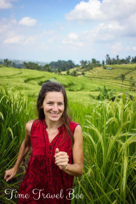 Dziewczyna w czerwonej sukience biegnie przez zielone pole ryżu. Bali, Indonezja.