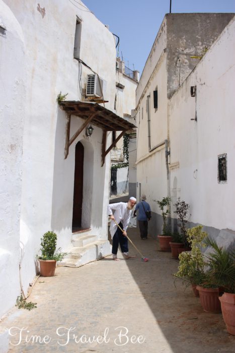 Sidi ramdane meczet w centrum Algieru, stary mężczyzna w tradycyjnym muzułmaskim stroju zamiata.