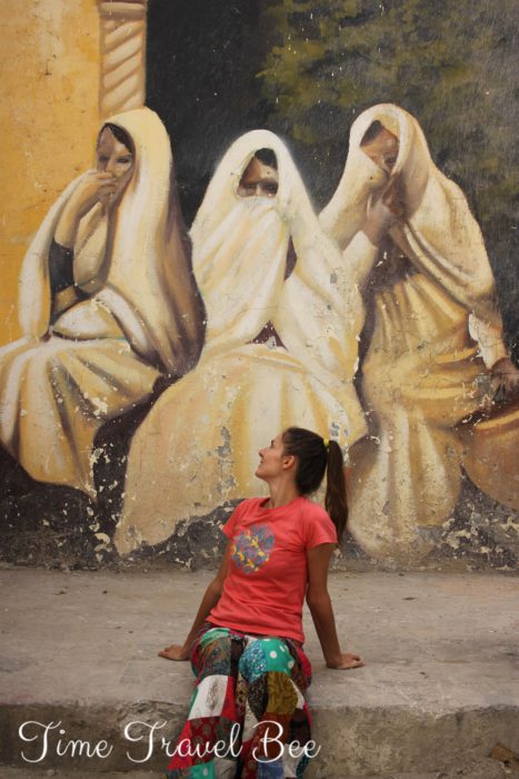 Kobiety w czadorach burkach w Algierii. Graffiti w algierze kasba polska dziewczyna w kolorowych strojach siedzie na ulicy Algieru.