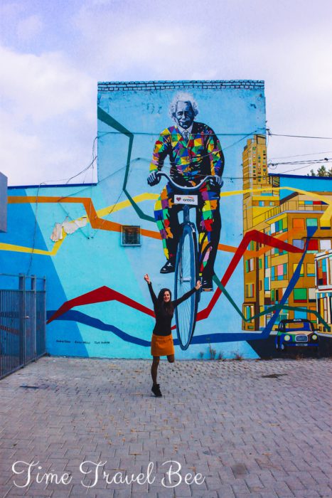 Atreet arts bucharest, mural with Ainstein on the bicycle. Girl jumping, colorful graffiti in the backgorund.