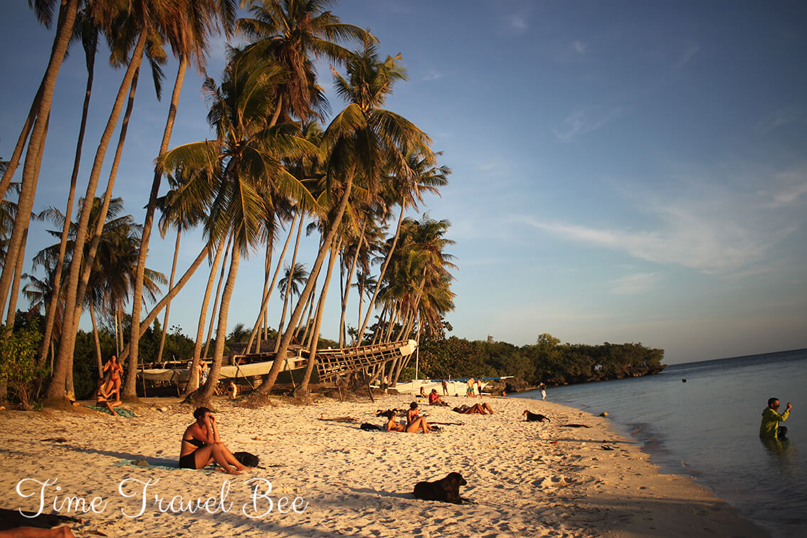 Złota godzina i zachód słońca na Siquijor. Dziewczyna na plaży pod palmami.