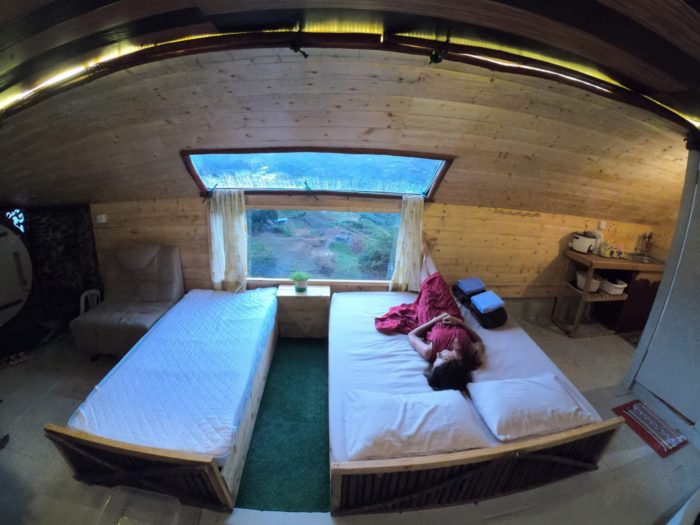 Chatka Hobbita w Malezji. Dziewczyna na łóżku w czerwonej sukni spogląda na góry.