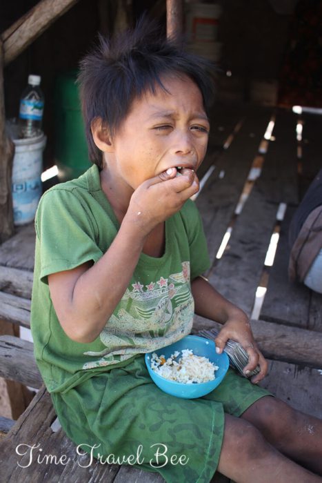 Biedny chłopiec Azjatycki je ryż w drewnianej chacie. Ludzie Bajau na Borneo.