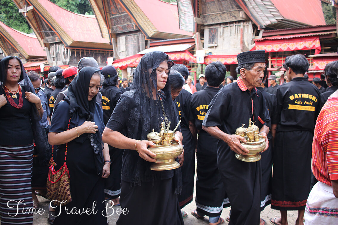 Pogrzeb w Toradży, kobiety niosące dary w tradycyjnej wiosce.
